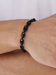 Close-up of a men's black stainless steel curb chain bracelet on a model's wrist