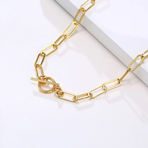 Detailed close-up of golden paperclip chain necklace with a classic OT toggle clasp