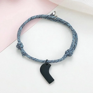 Detail of adjustable blue-grey braided rope bracelet with magnetic clasp and heart pendant