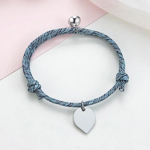 Close-up of woven couple bracelet with blue and black ropes and heart charm