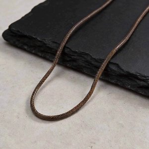 Close-up of dark brown woven wax cord necklace with detailed braid texture on stone