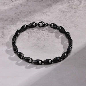 Detail of sleek black stainless steel links with a secure lobster clasp on stone surface