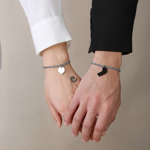 Close-up of matching woven heart puzzle bracelets for couples in black and white finish