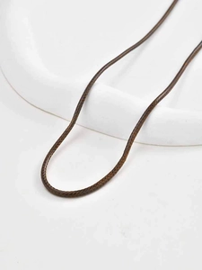 Detailed close-up of brown braided wax cord necklace on white ceramic display