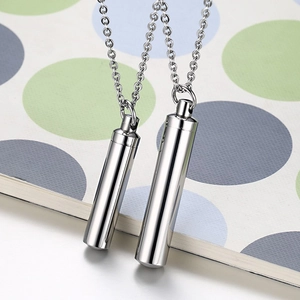 Macro shot of two cylindrical stainless steel perfume pendant necklaces with high polish