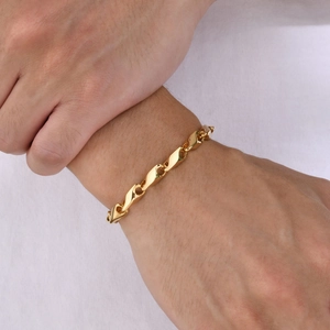 Close-up of polished gold-tone twisted link bracelet on a male wrist with mirror finish