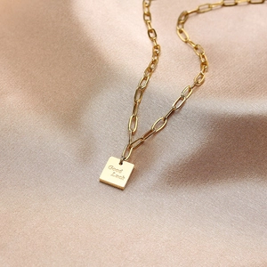 Collier trombone en acier titane doré avec un pendentif carré gravé Good Luck