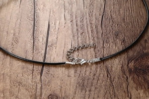 Close-up of black waxed cord necklace with silver lobster clasp and extension chain