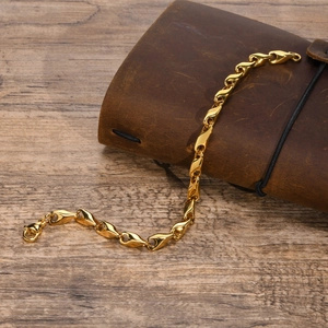 Close-up of golden stainless steel twist chain bracelet with secure lobster clasp on wood