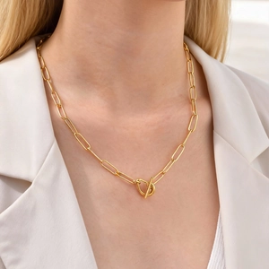 Elegant gold paperclip chain necklace with a toggle clasp worn with a white blazer