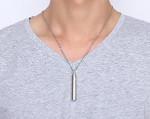 Close-up of a silver cylindrical pendant necklace worn on neck for minimalist style