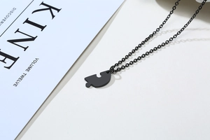 Close-up of black puzzle piece pendant with matte finish and matching thin link chain