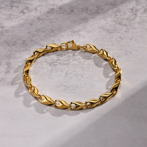 Macro detail of golden link bracelet featuring drop-shaped geometric links and lobster clasp