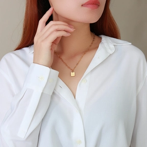 Collier minimaliste en acier doré avec pendentif carré Good Luck porté par un mannequin