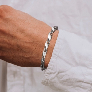 Close-up of a men's stainless steel curb chain bracelet styled with a white shirt