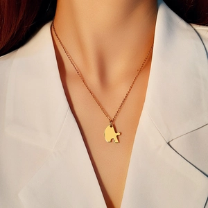Macro view of gold jigsaw puzzle pendant necklace with high polished finish on model