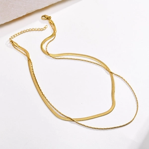 Detail of golden double-layer necklace with flat herringbone and fine cable chains