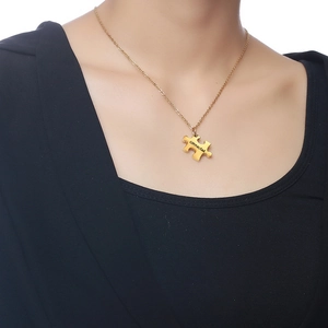 Detail of a gold puzzle piece necklace engraved with 'connected' worn on a model