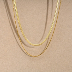 Detail of layered golden stainless steel snake chain and fine link necklace set
