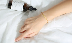 Gros plan d'un bracelet minimaliste en acier titane doré avec plaque sur tissu blanc