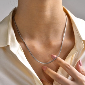Primo piano di una collana a catena a serpente argento su modella con camicia satin