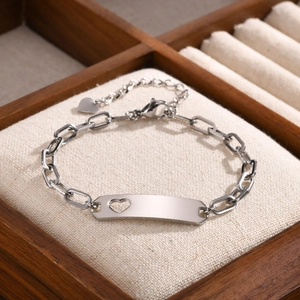 Macro detail of silver stainless steel kids bracelet with heart cutout plate on linen