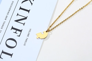 Detail of a gold heart puzzle pendant with a polished fine chain on a minimalist magazine