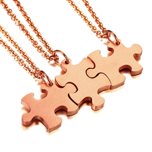 Macro shot of rose gold puzzle piece pendants with brushed metal finish and O-chains