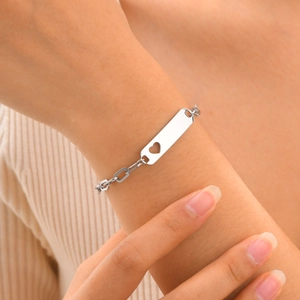 Macro detail of silver steel kids bracelet featuring a hollow heart on a polished bar