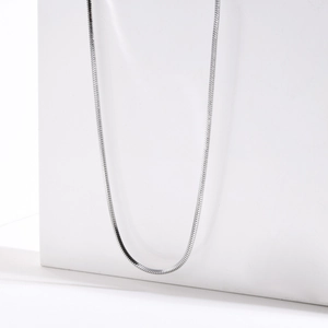 Dettaglio ravvicinato di una collana a catena a serpente lucidata argento su supporto