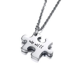 Macro shot of polished silver puzzle pendant with we will engraving on stainless steel chain