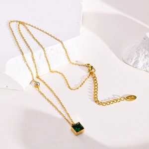 Macro shot of gold square emerald green necklace featuring K18 engraved metal tag
