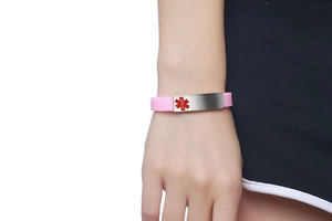 Nahaufnahme vom rosa Silikon-Notfallarmband mit Edelstahl-ID-Platte am Handgelenk