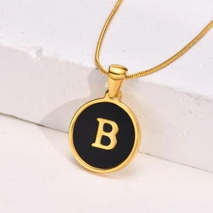 Detailed close-up of golden letter B pendant with black enamel finish on snake chain