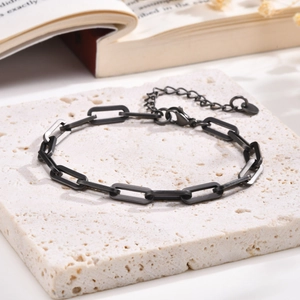 Macro shot of matte black paperclip link bracelet with adjustable lobster clasp on stone