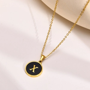 Detailed close-up of a golden round pendant with a black center featuring a golden letter X