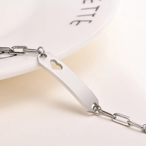 Macro detail of stainless steel bracelet with engraved bar and heart cutout detail