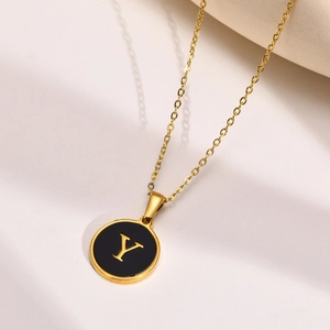 Close-up of golden letter Y necklace with black enamel pendant on minimalist background