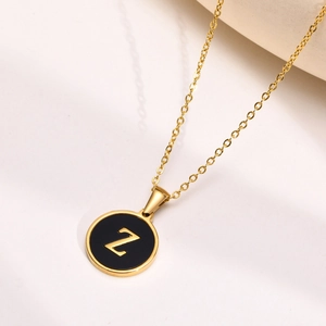 Close-up of gold stainless steel necklace featuring a black round pendant with letter Z