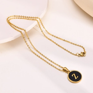 Macro detail of gold initial Z pendant with black enamel on a fine chain necklace