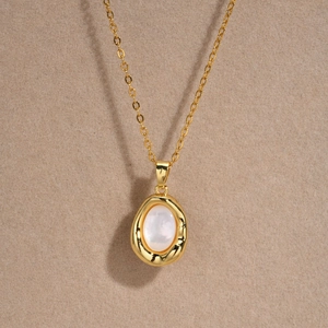 Detailed view of an irregular 18K gold-plated necklace with a white shell oval pendant