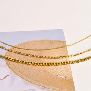 Détail de colliers dorés à mailles serpent, torsadées et cubaines disposés en parallèle