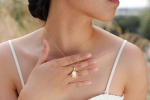 Close-up of a 18K gold-plated shell pendant necklace worn by a model in natural light