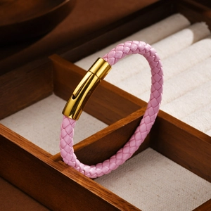 Détail d'un bracelet en cuir tressé rose avec un fermoir magnétique en or poli
