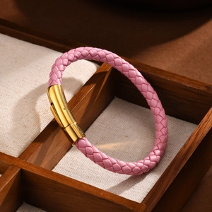 Détail d'un bracelet en cuir tressé rose avec fermoir doré sur une boîte à bijoux
