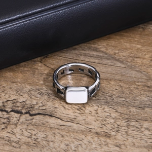 Macro view of silver geometric ring featuring a flat square face and cutout side details