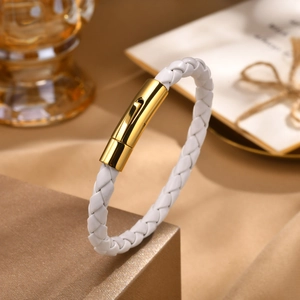 Détail du bracelet en cuir tressé blanc avec un fermoir cylindrique en métal doré poli