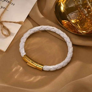 Détail d'un bracelet en cuir tressé blanc avec un fermoir magnétique en métal doré