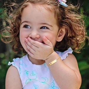 Golden stainless steel kids ID bracelet with hollow heart charm on child model's wrist