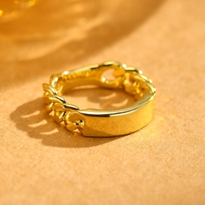 Macro shot of gold chain ring with a smooth rectangular plaque on warm textured background
